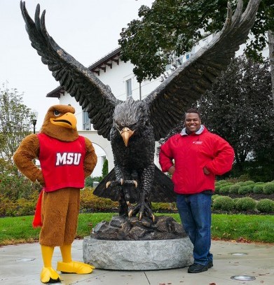 A photo of Rahjon White with Montclair State’s mascot and statue. 
