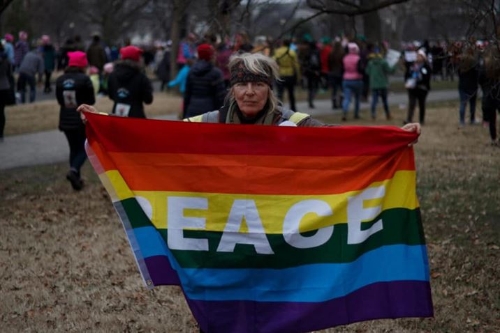 A woman holds up a flag advocating for peace at the march in D.C. Photo Credit: Michael Gorczyca