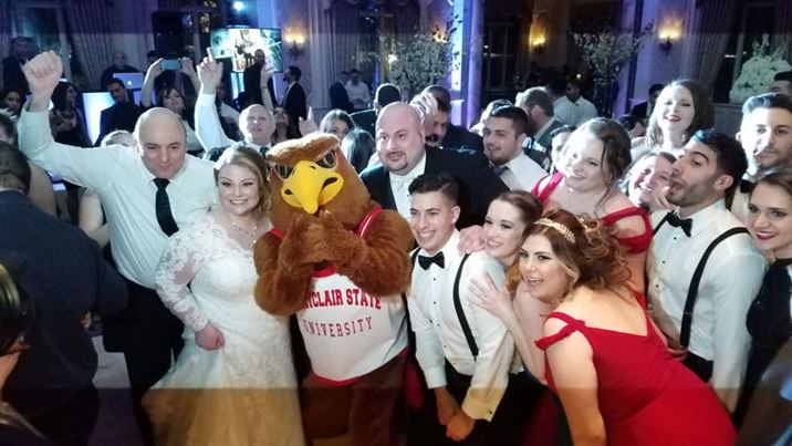Newlyweds George Juzdan and Sheena Higgins pose with family, friends and Rocky the Red Hawk at their reception. Photo courtesy of Michelle Handal
