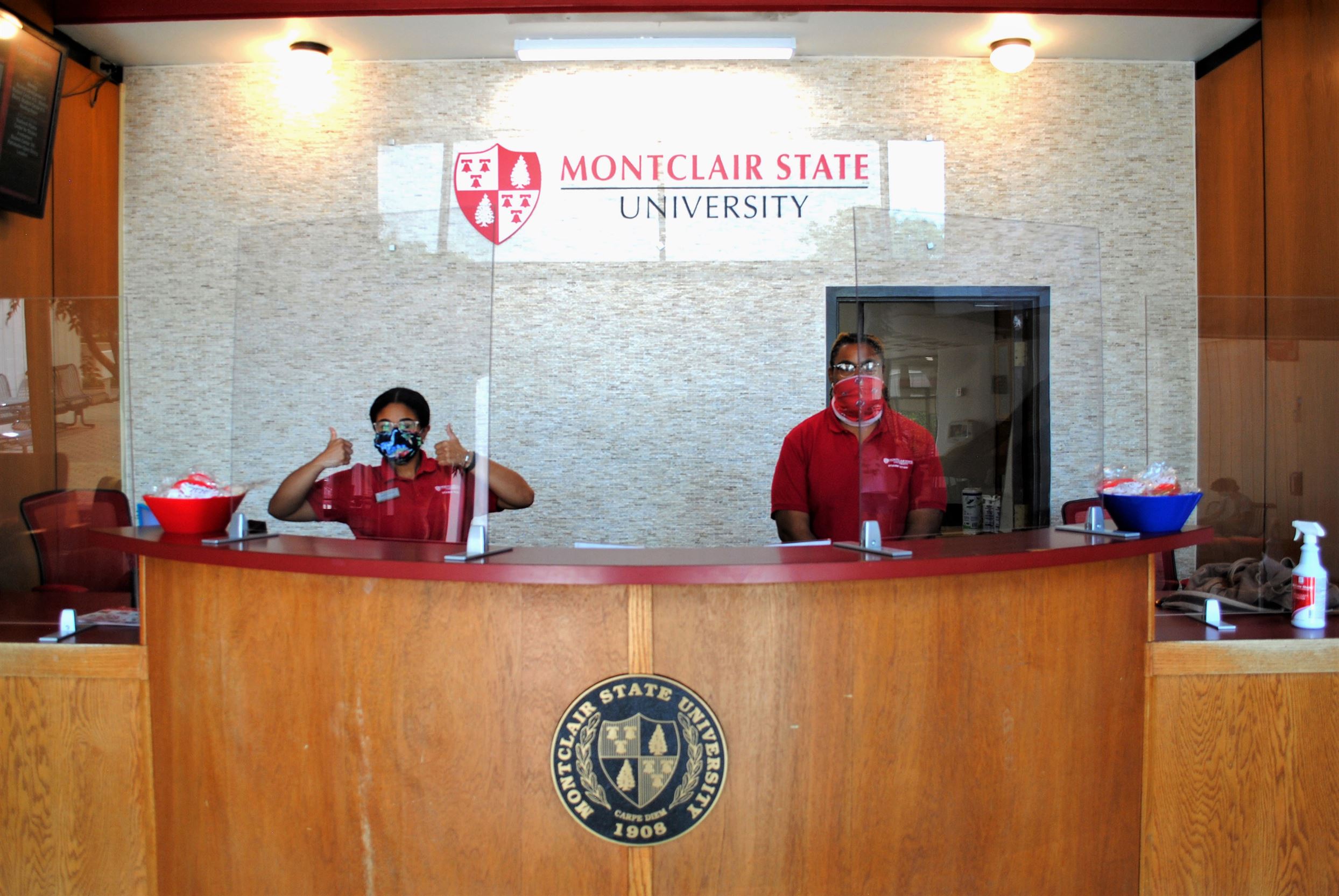 In the student center, junior psychology major Genesis Garcia and senior Marcell Jenkins wear face coverings behind the partition at the student life service desk on the first day of classes. Michael Giannotti | The Montclarion