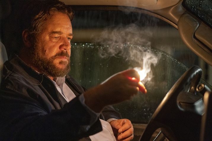 The Man, played by Russel Crowe, stares at a match as the rain pours into his car. Photo courtesy of Solstice Studios and Ingenious Media.