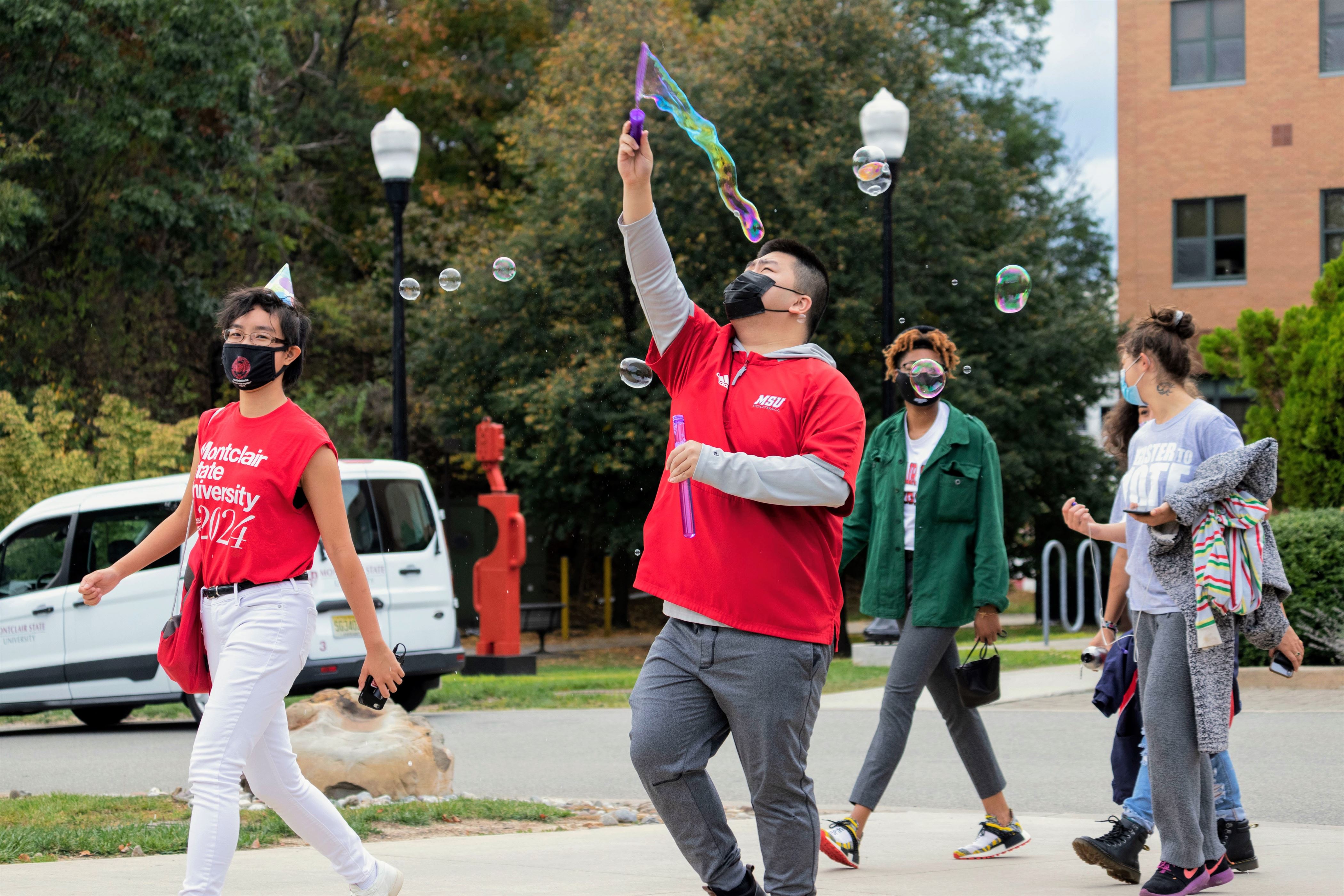 A Montclair State student wafts a bubble wand through the air to create bubbles during Rocky's birthday parade, near Dickson Hall. Sunah Choudhry | The Montclarion