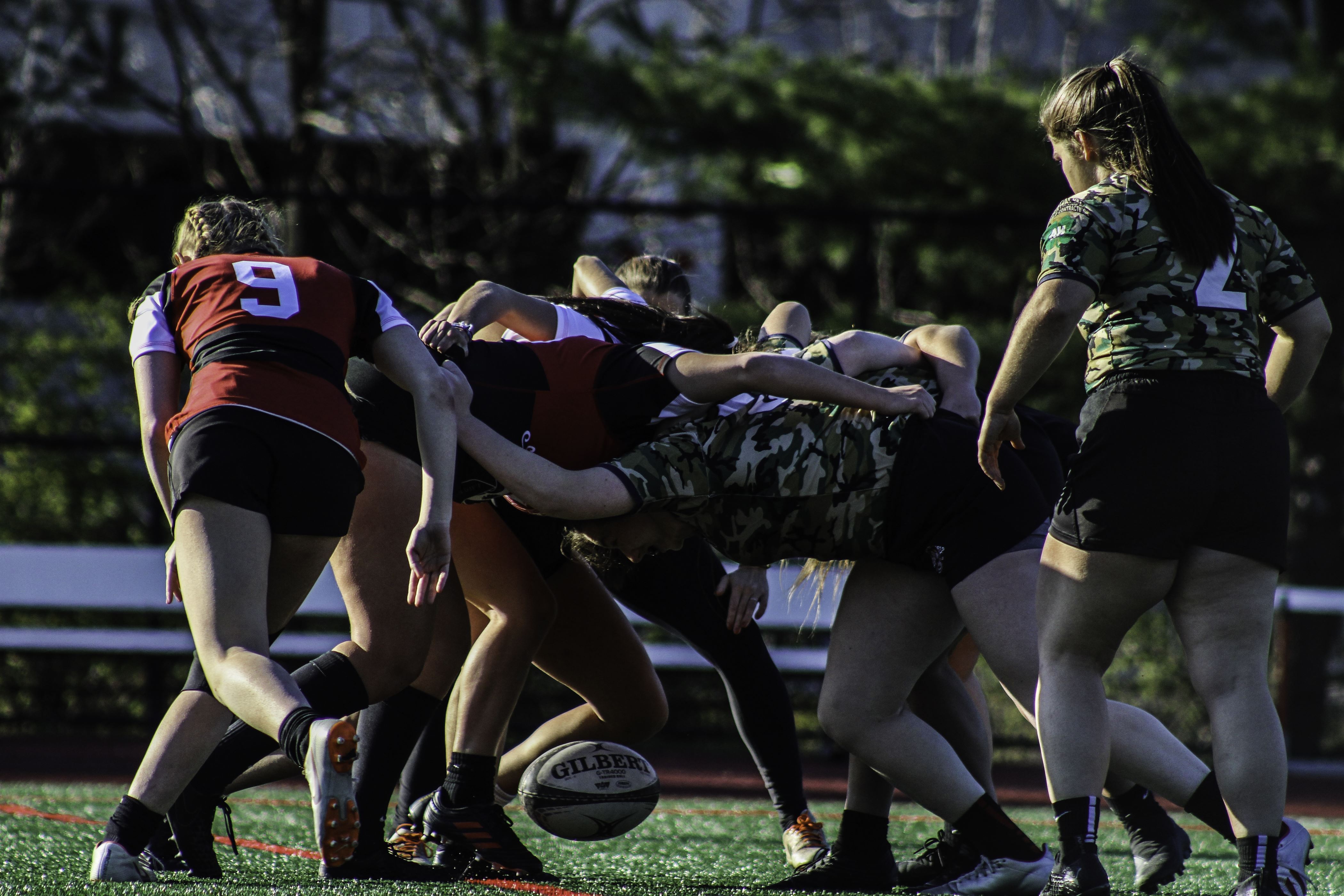 Both teams battle over the ball in a scrum, using their feet to knock the ball towards their side/