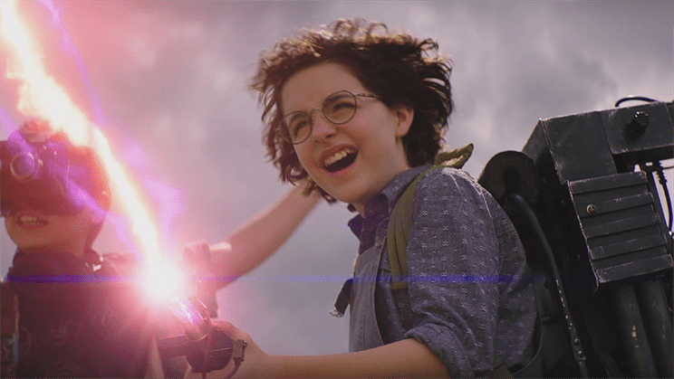 Phoebe, played by Mckenna Grace, blasts a ghost with a proton pack while Podcast, played by Logan Kim, watches. Photo courtesy of Columbia Pictures