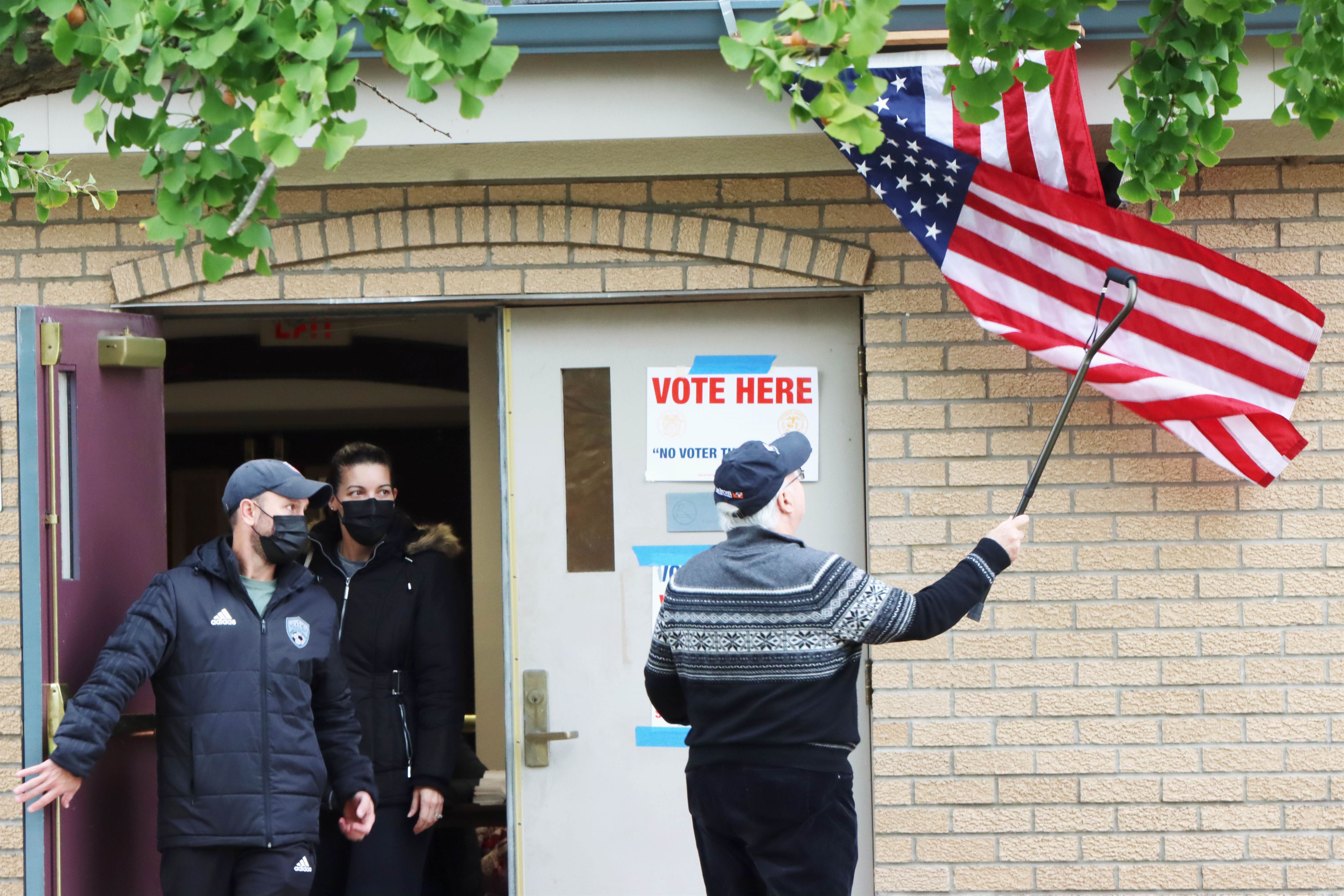 Edward Bonner (right) from Wanaque, New Jersey fixing the flag with his cane outside the Wayne Public Library where voting is taking place. Photo Courtesy of Dylan Rottkamp