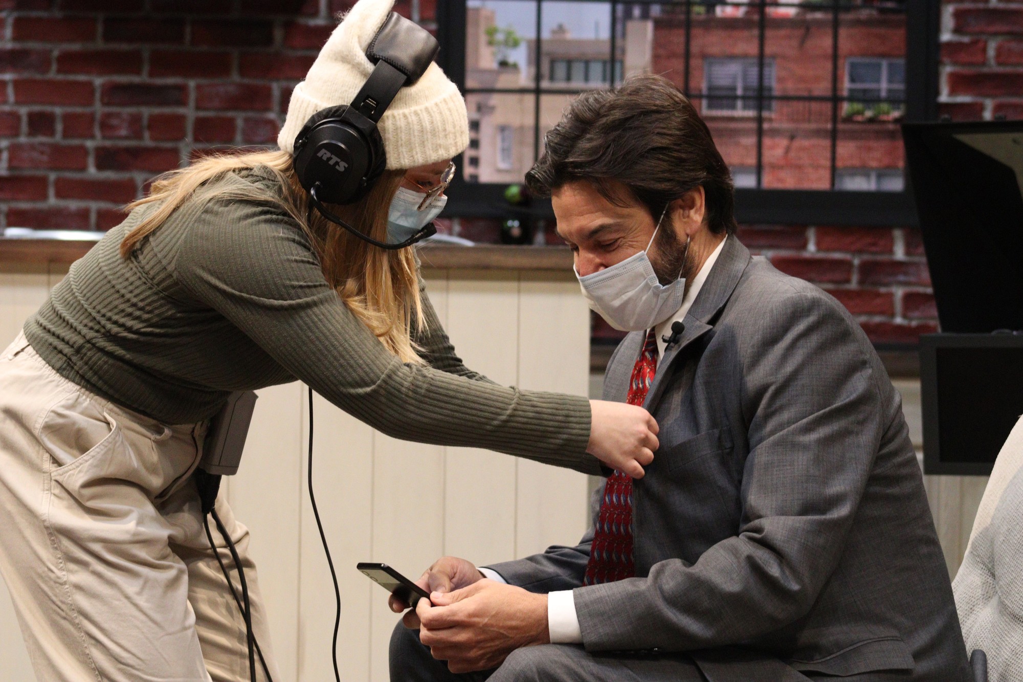 Jess Pochek, a senior film and television major, setting up a microphone on Dr. Koppell before a student meeting while he checks Tik Tok on his phone. John LaRosa