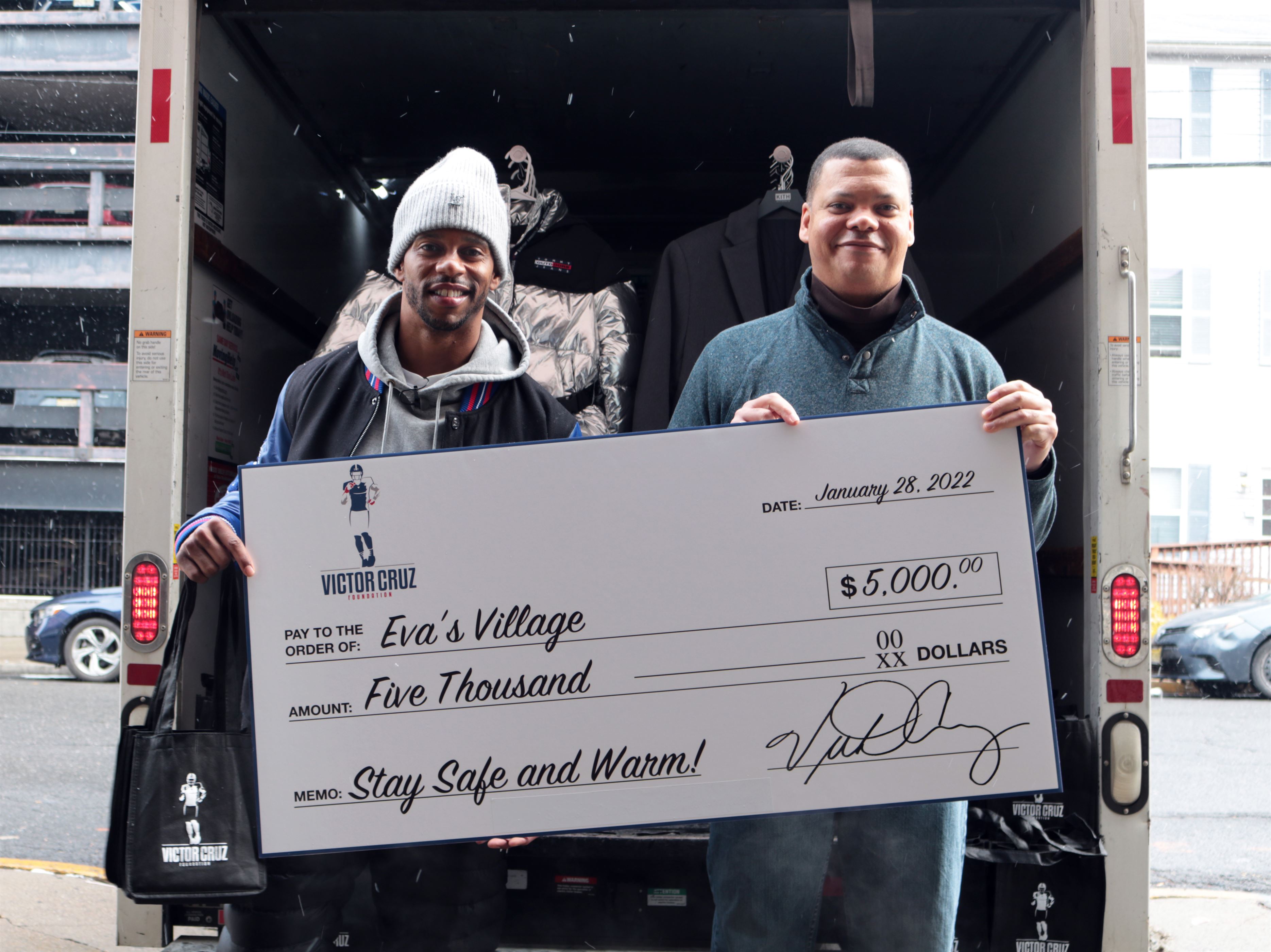 Victor Cruz (left) gives donations to the CEO of Eva's Village, Howard L. Haughton Photo courtesy of Monica Fernandez-Prato