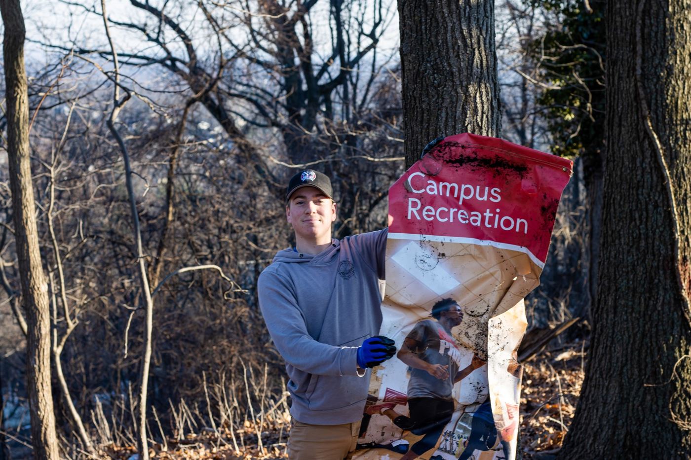 (student name here) holds up a Campus Recreation poster that was found in the woods. Julian Rigg | The Montclarion