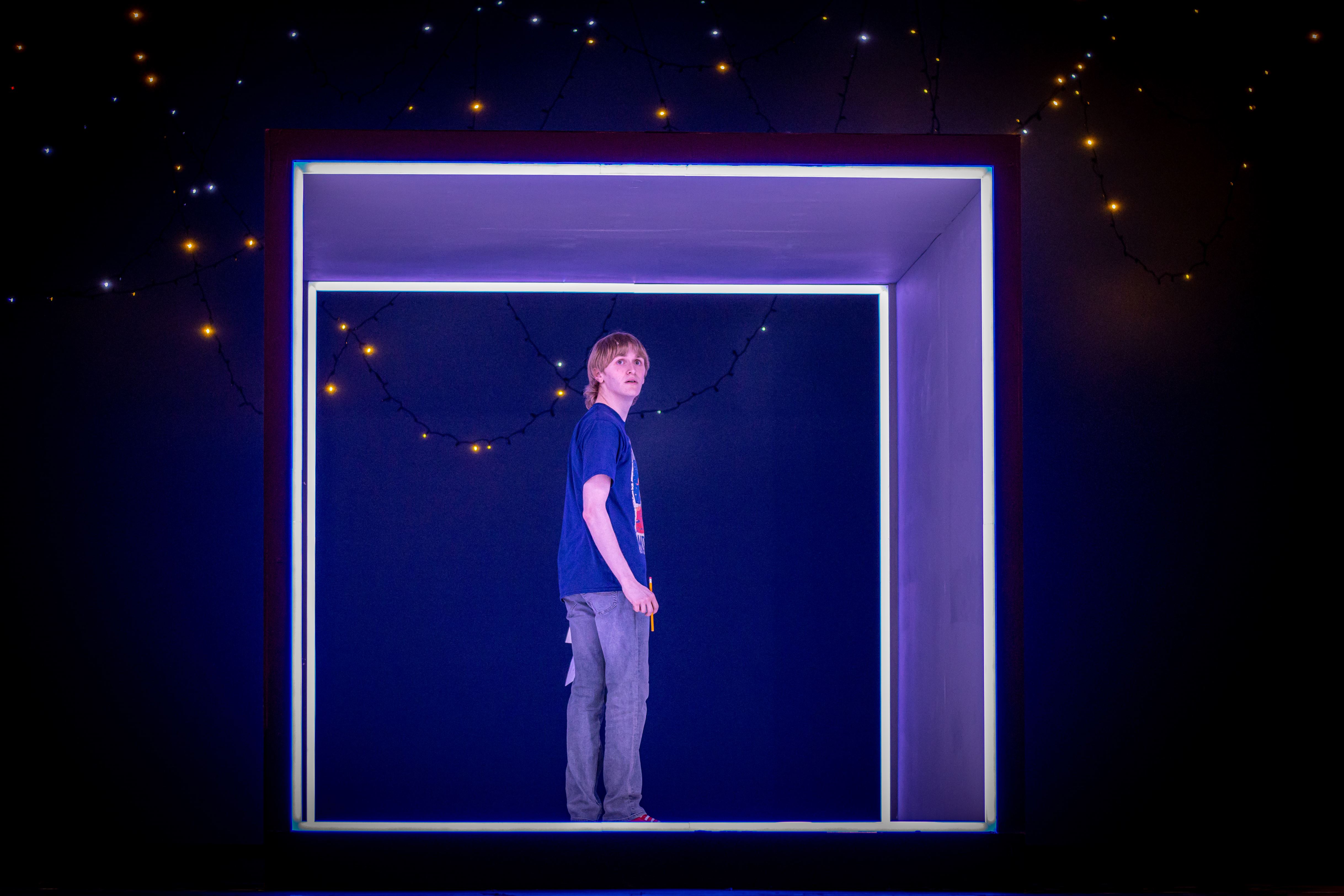 Christopher (Andrew Linden) stands alone in an illuminated cube.