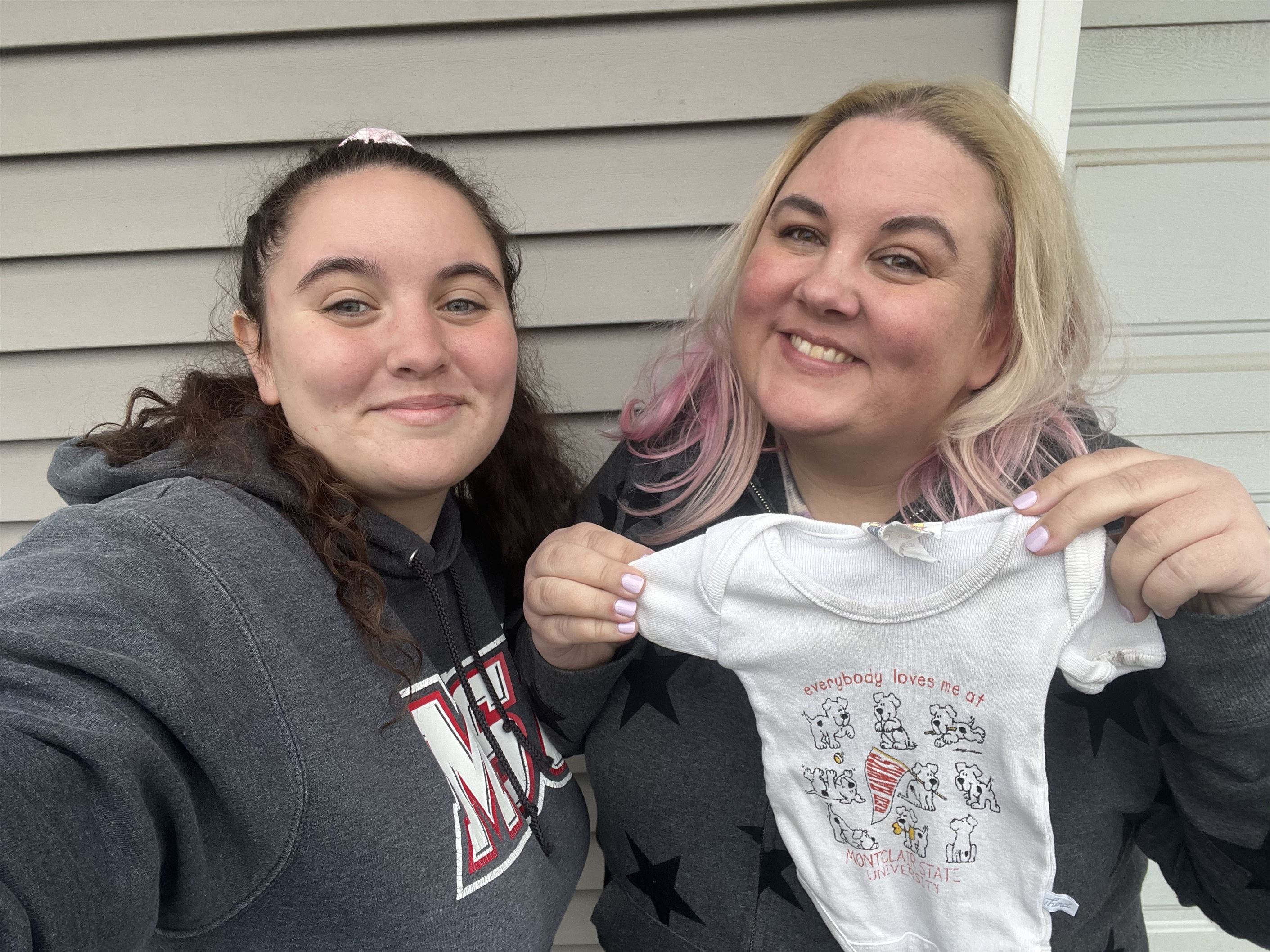 Diana Sisk-Gritz and her mother, Stefanie Mulley, holding up a Montclair State onesie Sisk-Gritz wore as a baby. Photo courtesy of Diana Sisk-Gritz