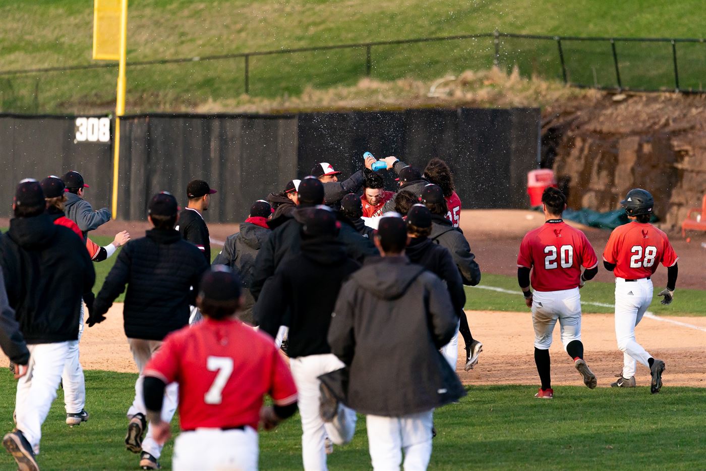 Teammates rush over to senior infielder Jason Moore after delivering the game-winning run. Chris Krusberg | The Montclarion