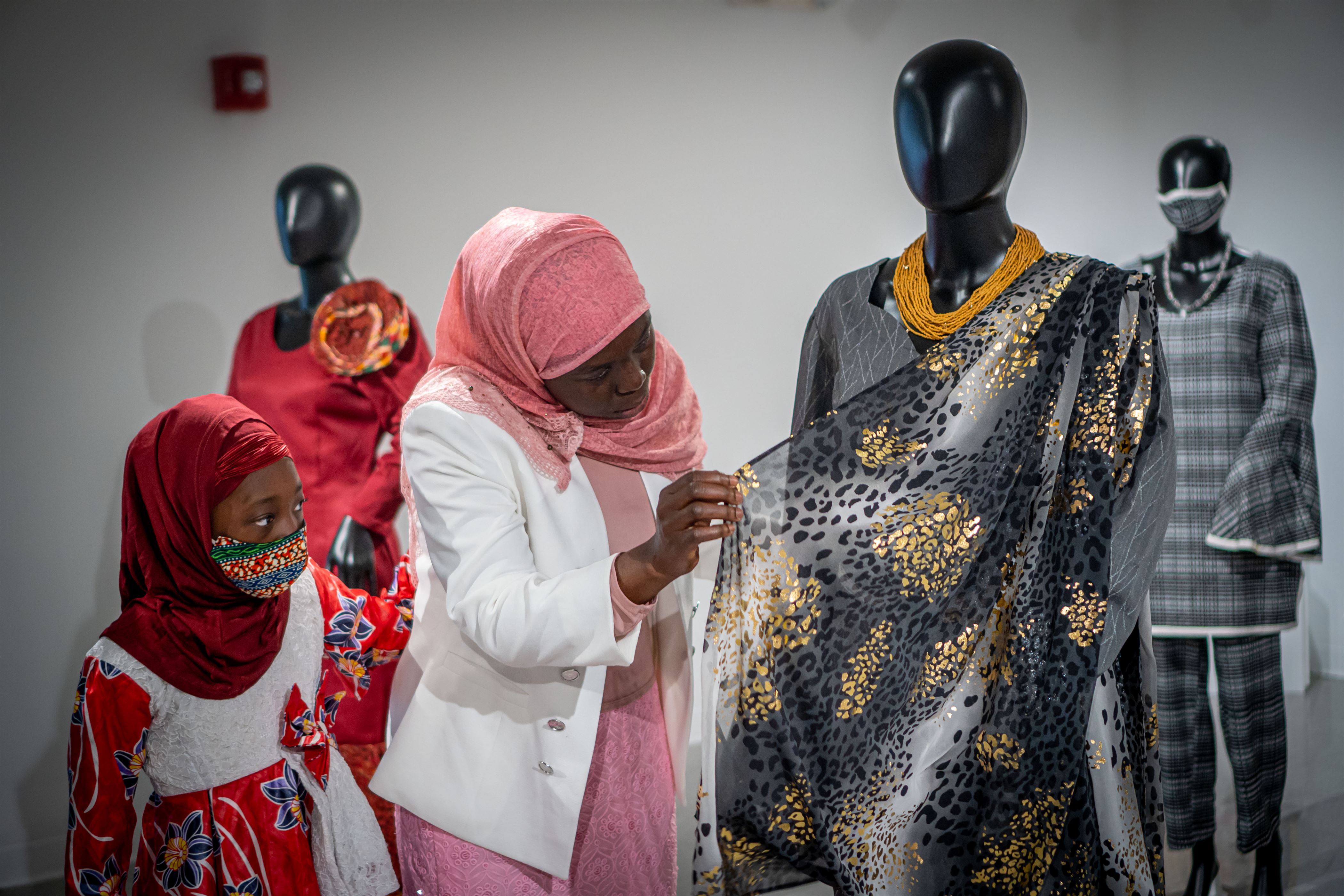 (From left to right): Nazeeha, Saphiatou Akondo's daughter, Saphiatou Akondo admires one of the looks in the collection. Lynise Olivacce | The Montclarion