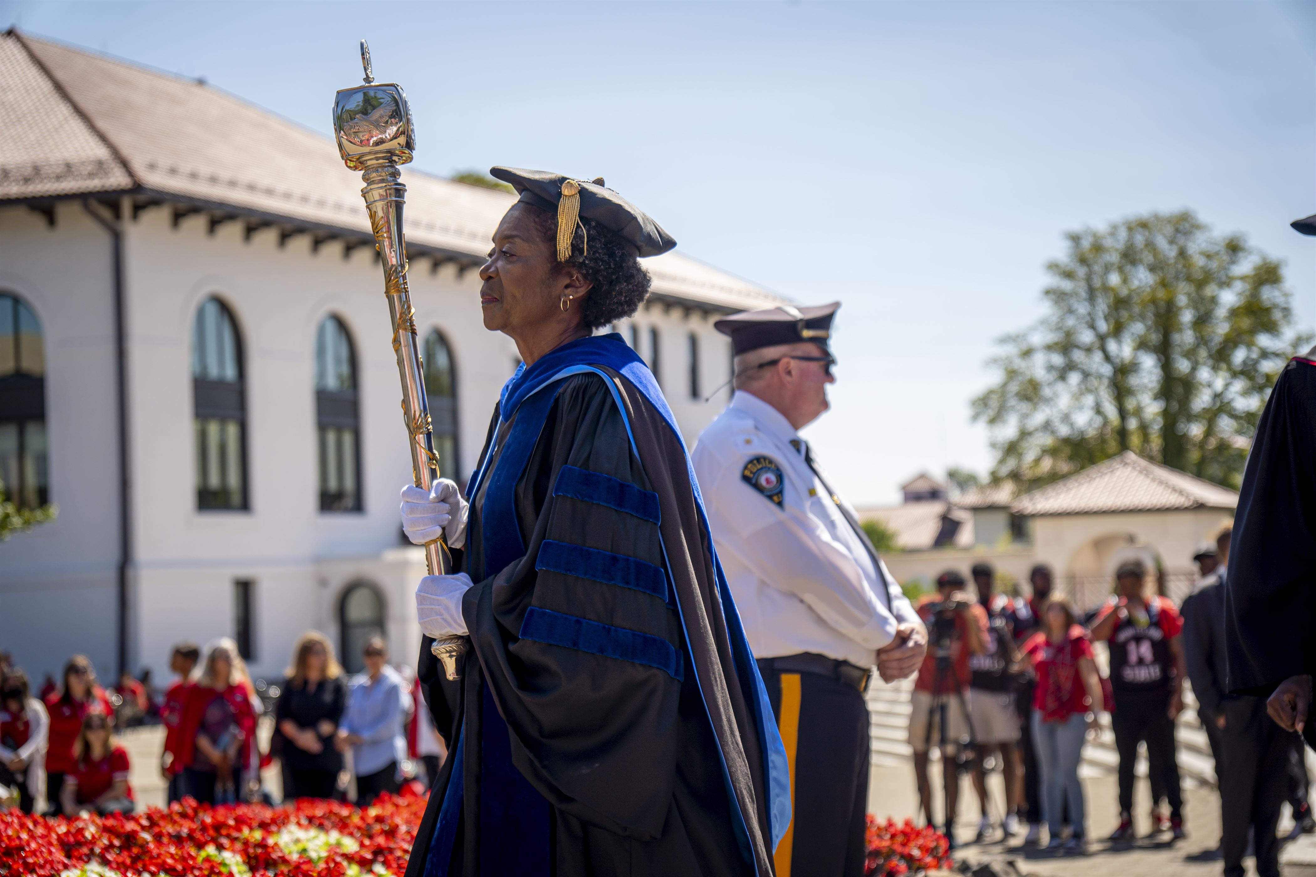 Grand Marshal Sandra Adams holds the university mace as she leads people to the Amphitheater. Lynise Olivacce | The Montclarion