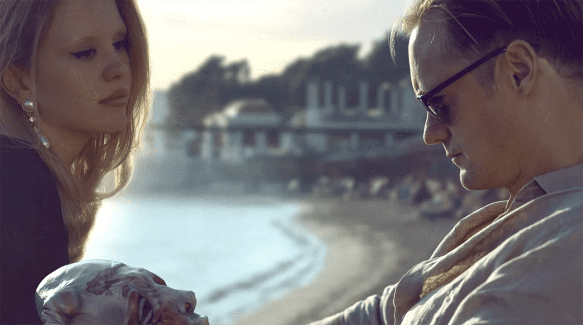 James (Alexander Skarsgård) and Gabi (Mia Goth) sit on the beach.