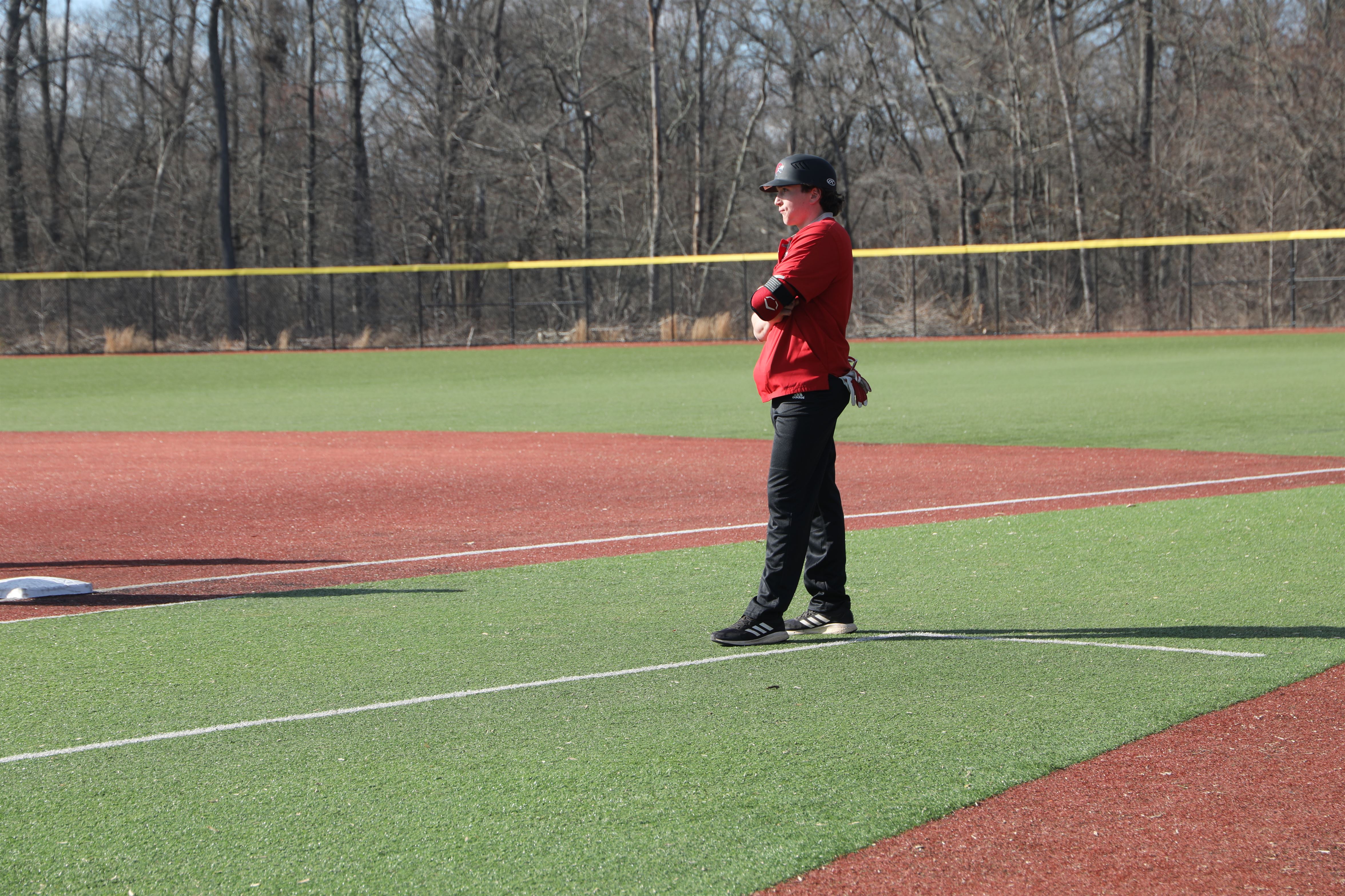 Assistant coach Joe Norton stands at the first base line and surveys the field. Photo courtesy of Gianna Daginis