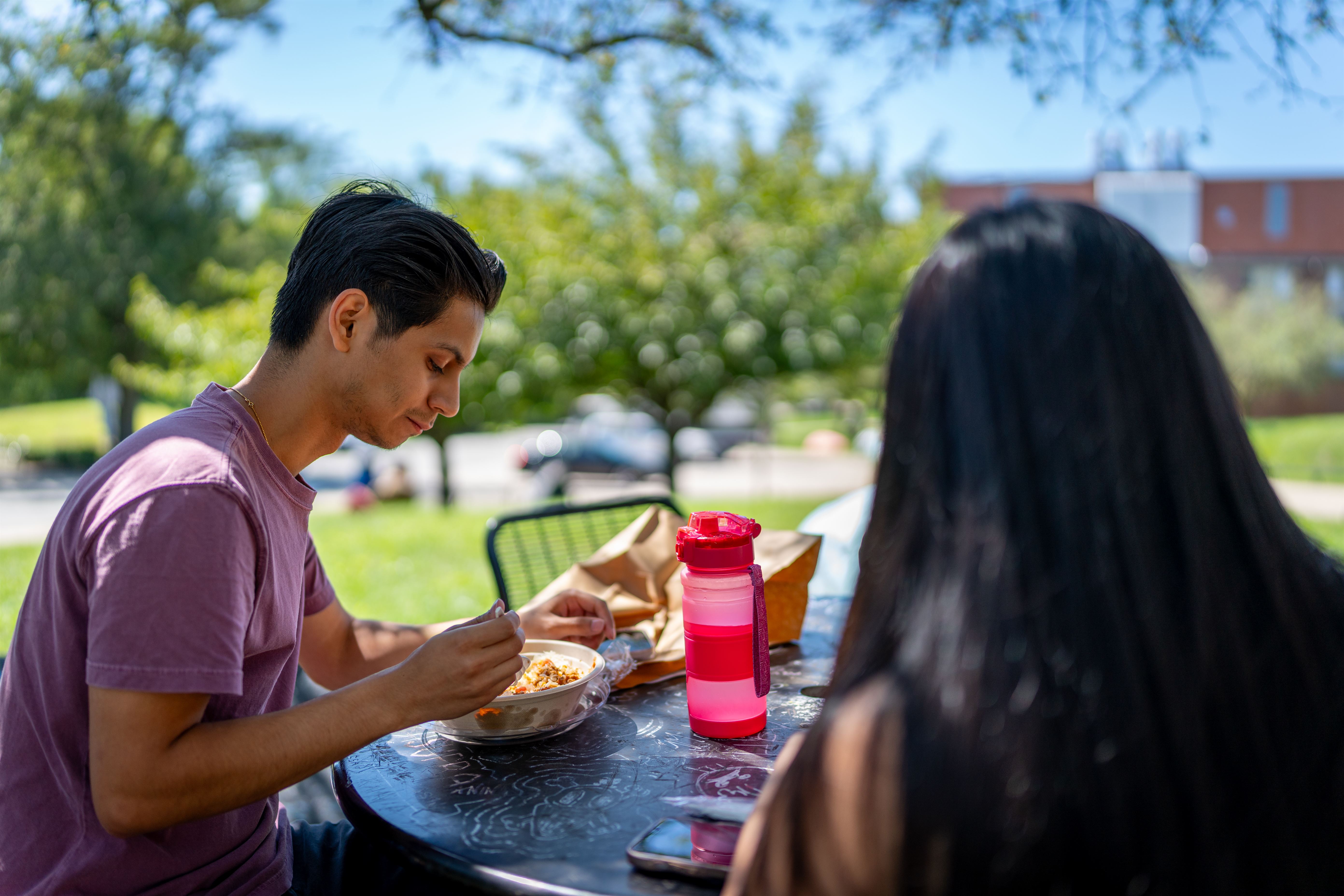 Daniel Ramos, a junior Biology major, and Kelly Du, a sophomore Computer Science major, eating Chick-N-Bap outside of Blanton Hall.