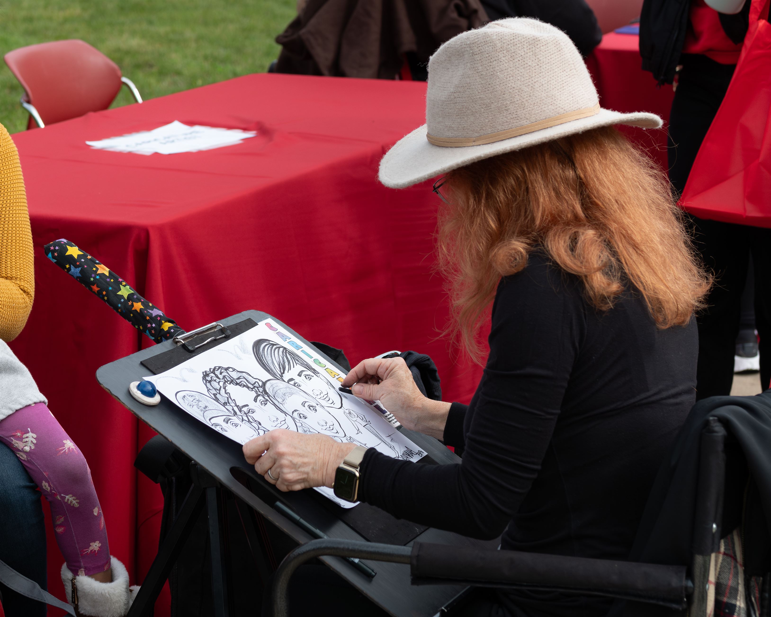 An artist draws for some people during Homecoming day festivities.  Photo courtesy of Maral Tutunjian
