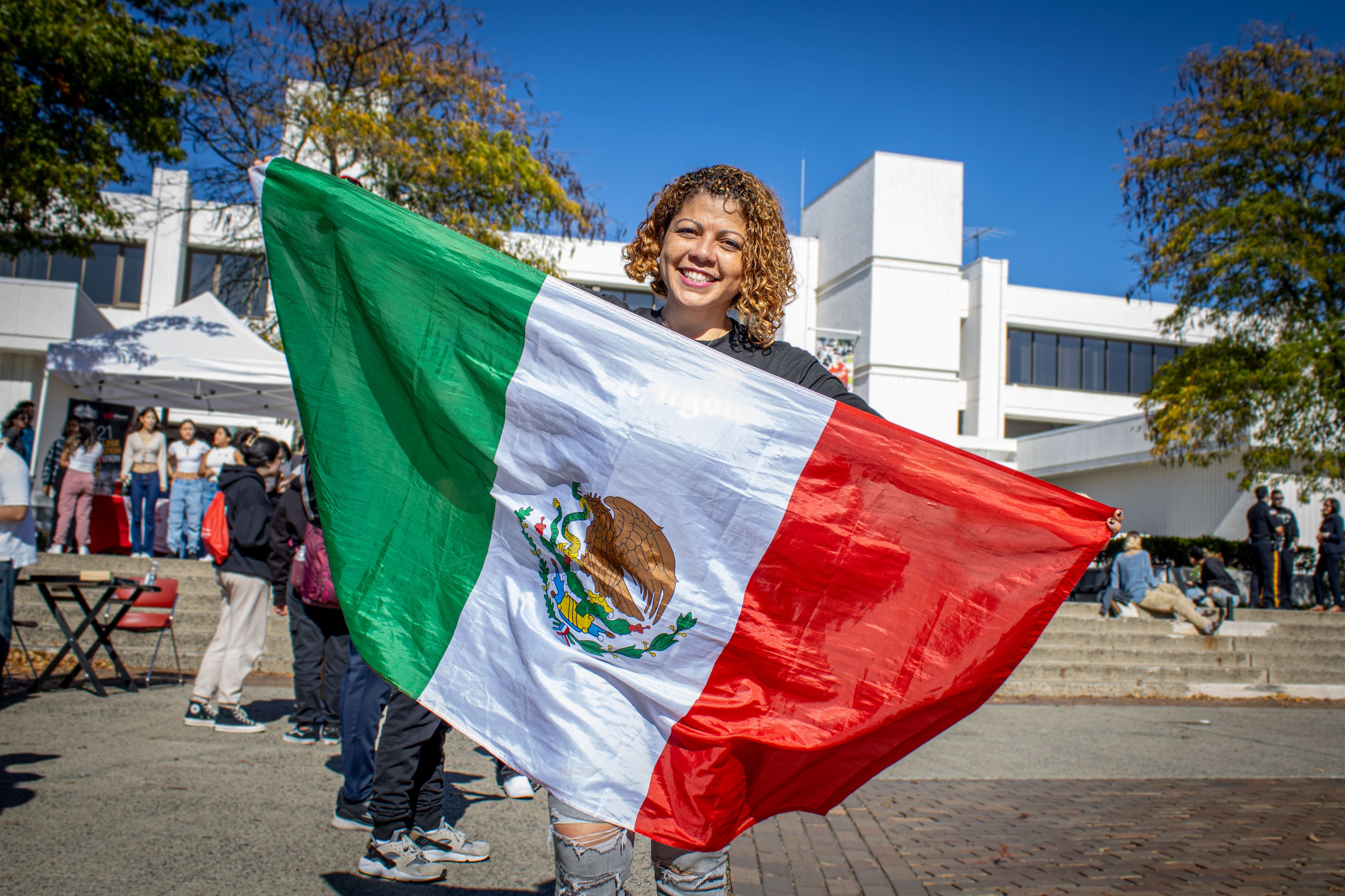 Photo of Iliana Woodhull, Senior majoring in family science and human development, with a concentration in family service, one minor in Psychology, and another in child advocacy, holding up a Mexican flag.  Dani Mazariegos | The Montclarion