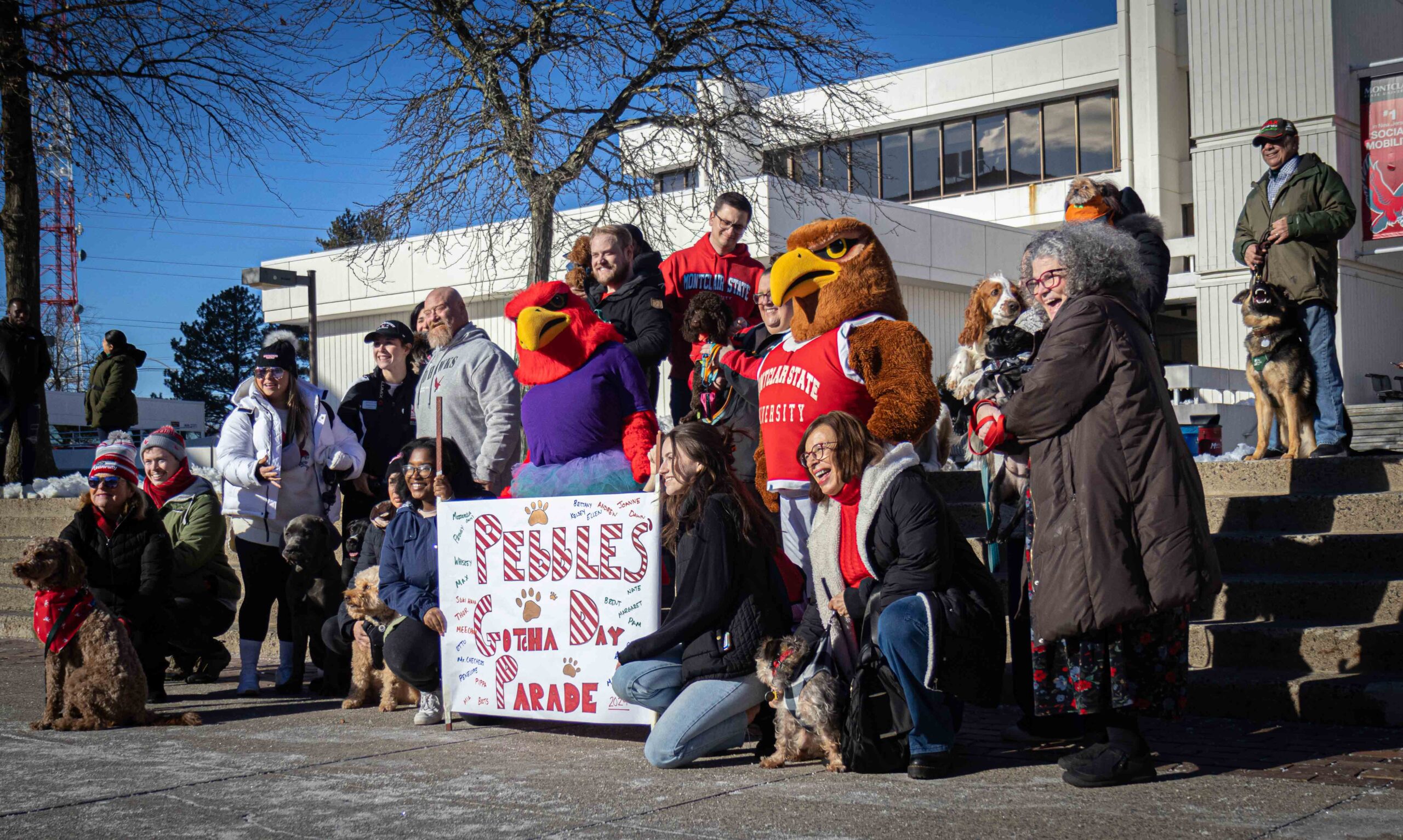 Pebbles and her puppy friends pose for a big group picture with a "Pebbles Gotcha Day Parade" sign. Allen Macaraeg | The Montclarion