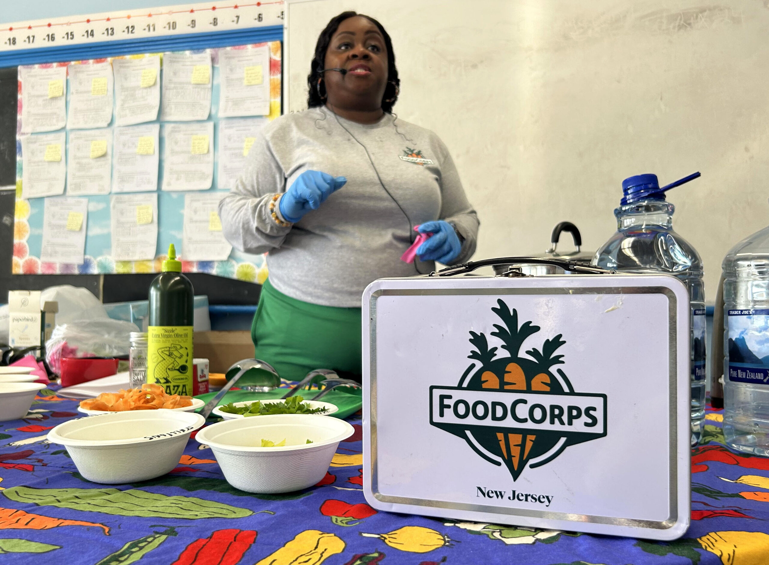 NEWARK, NEW JERSEY 03–14–2024 FOODCORPS LESSON: FoodCorps member, Bridgette Byrd, stands at the front of a classroom in Hawthorne Elementary School in Newark, NJ. She is teaching a class of 5th graders the importance of eating clean and providing them with the ingredients and instructions needed to make a vegetable soup.