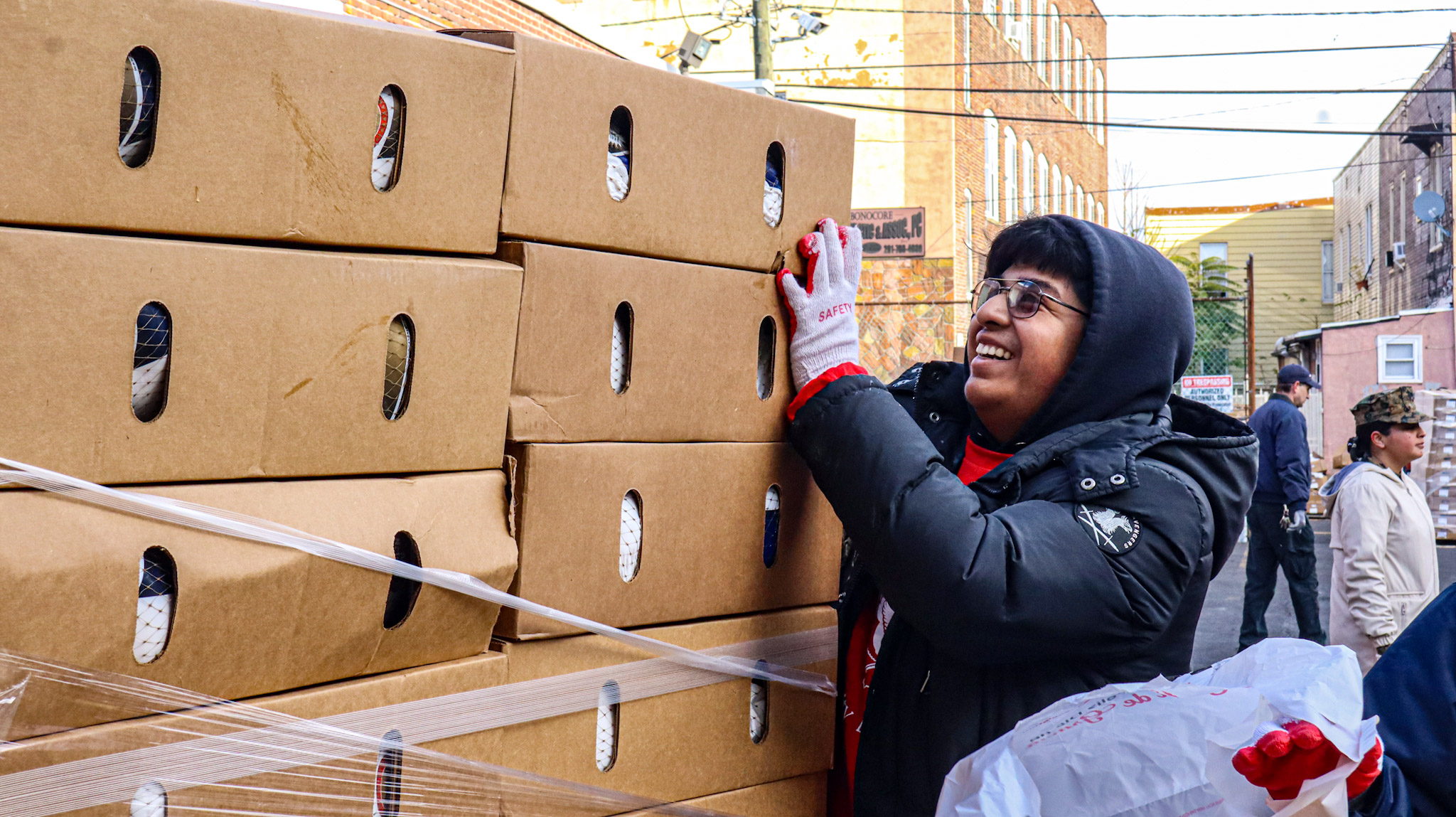 A student volunteer grabbing the turkey boxes to store them in a bag.