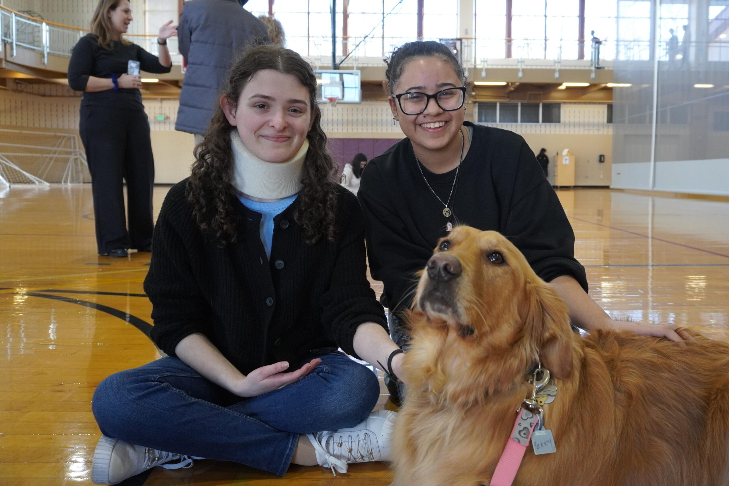 Two students pose with Penny, a therapy dog from Creature Comfort Pet Therapy, in the Montclair State Recreation Center Gym. Jordan Reed | The Montclarion