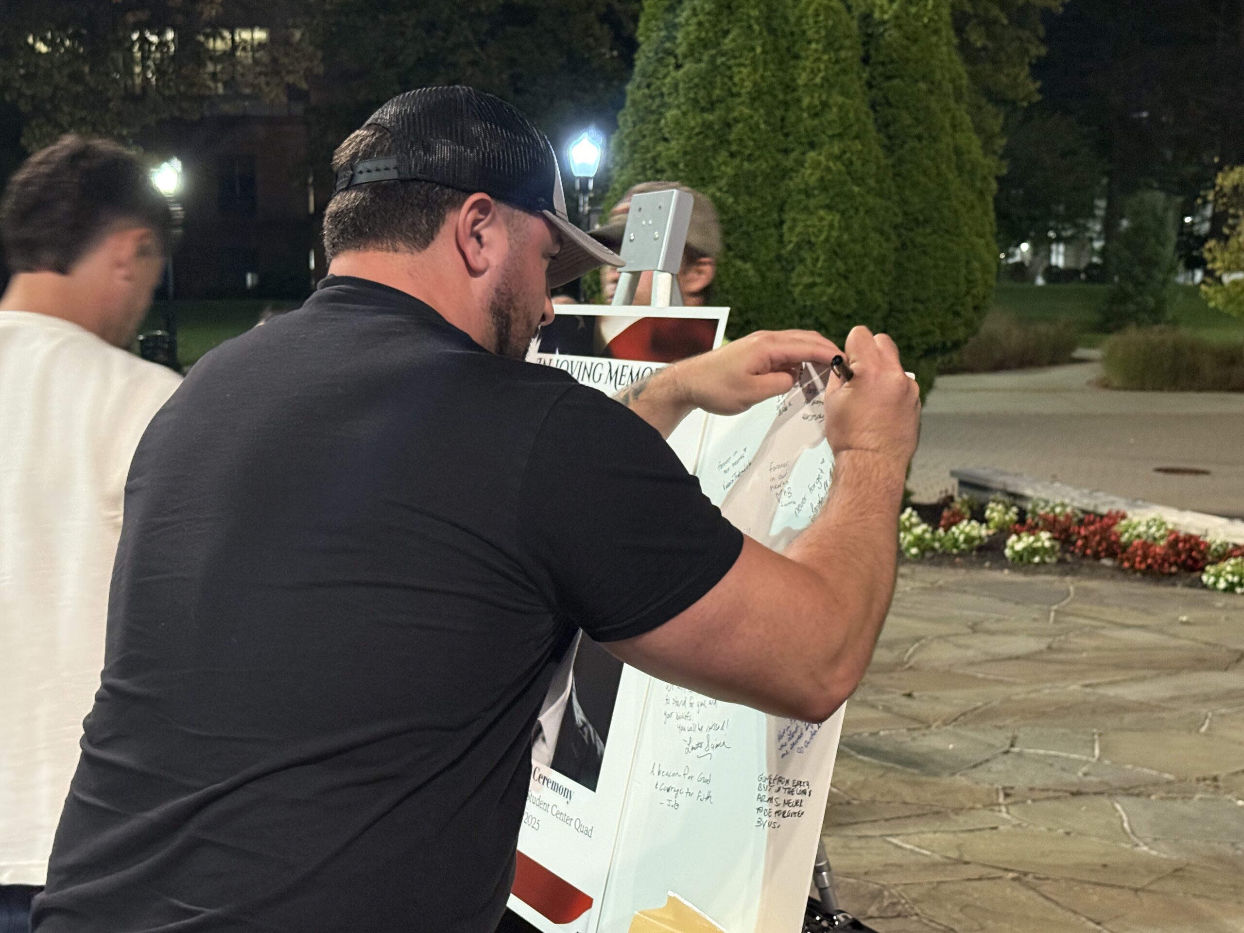 Attendee at the Charlie Kirk vigil ceremony signing the poster.