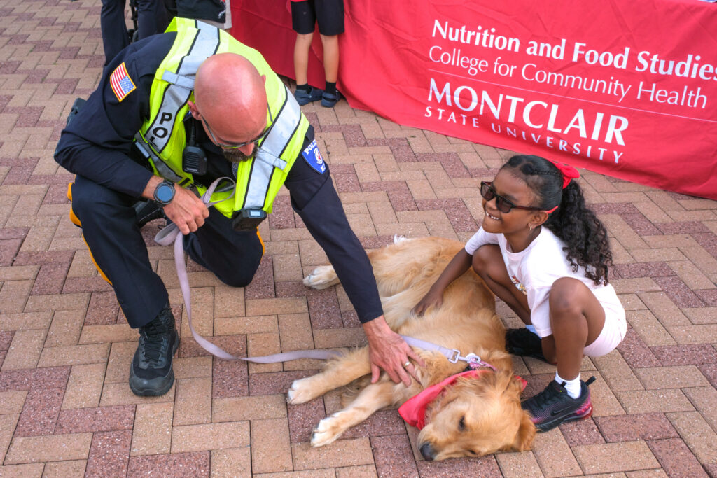 Little girl and Montclair State Police petting K9 at homecoming, Saturday, Oct. 3, 2026.